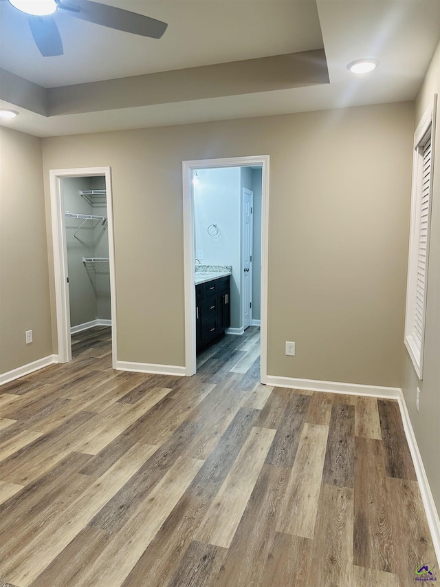 325 Peach Cir, Fort Valley, GA 31030 - unfurnished bedroom featuring a walk in closet, wood finished floors, connected bathroom, a closet, and ceiling fan
