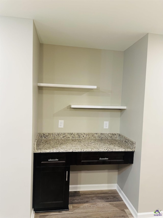 325 Peach Cir, Fort Valley, GA 31030 - kitchen with open shelves, wood finished floors, dark cabinets, built in study area, and light stone countertops