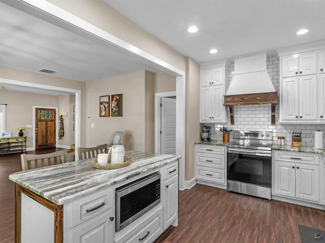 kitchen with visible vents, decorative backsplash, custom exhaust hood, white cabinets, and appliances with stainless steel finishes