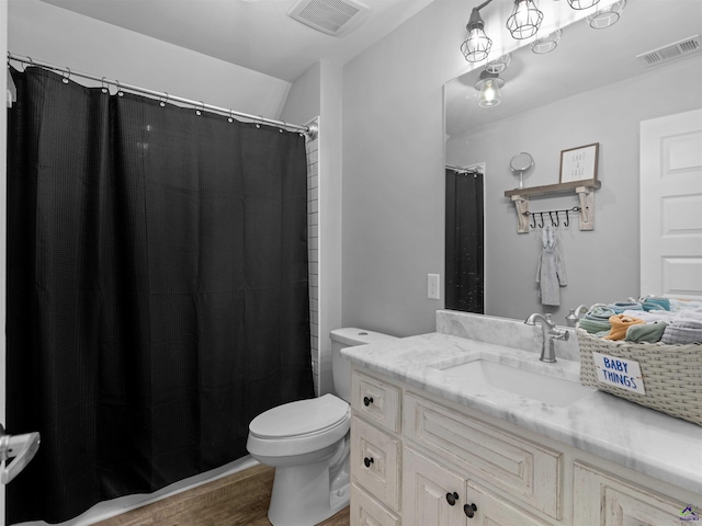 full bath featuring toilet, visible vents, wood finished floors, and vanity