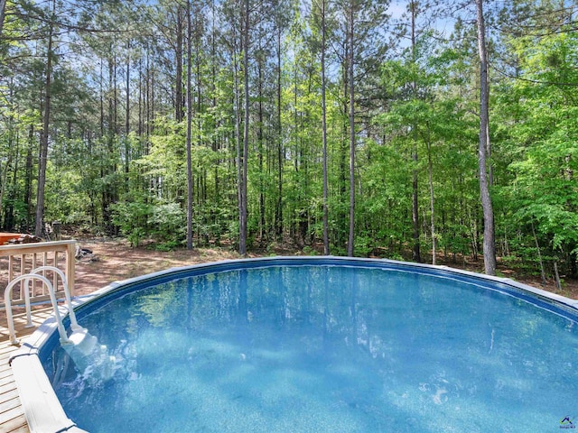 outdoor pool featuring a deck and a wooded view