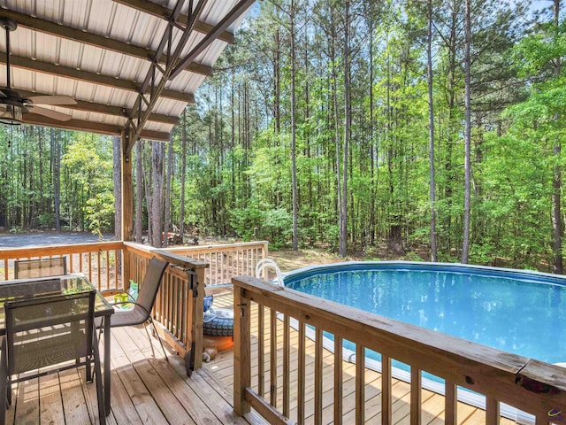 exterior space with a forest view, a ceiling fan, and a wooden deck