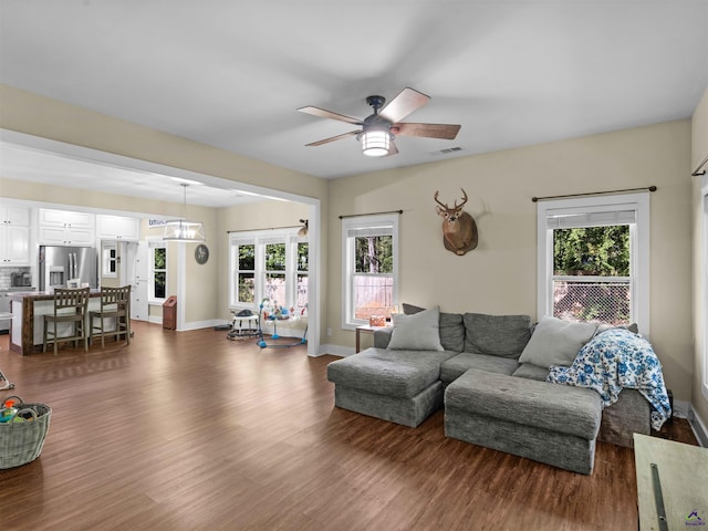 living area featuring plenty of natural light, a ceiling fan, and dark wood-style flooring