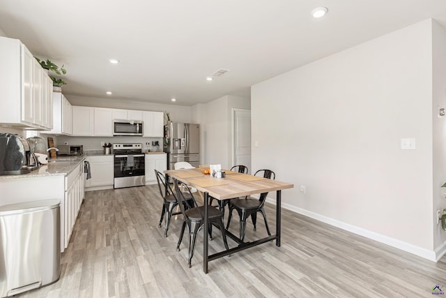 dining room featuring baseboards, recessed lighting, and light wood-style flooring
