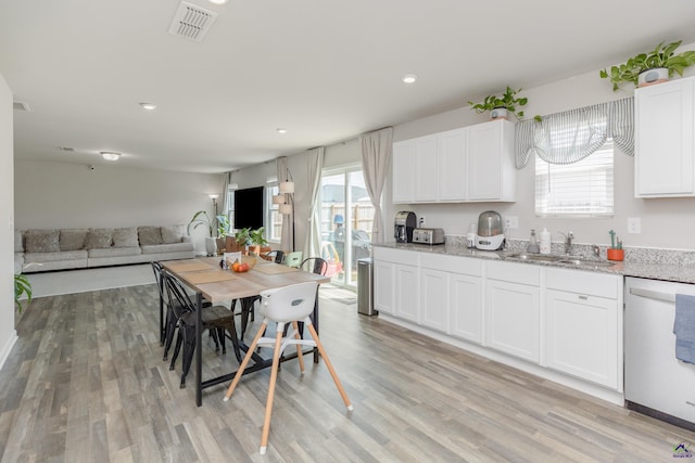 kitchen featuring visible vents, dishwasher, a sink, light wood finished floors, and white cabinetry