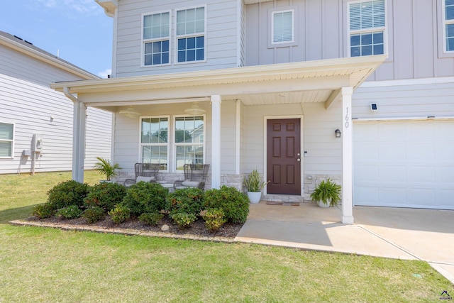 view of exterior entry featuring covered porch, board and batten siding, a lawn, a garage, and stone siding