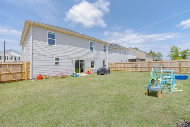 back of house with a yard and a fenced backyard