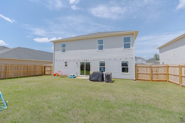 back of house with a fenced backyard and a yard