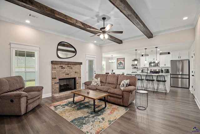 living area with beam ceiling, dark wood finished floors, ceiling fan with notable chandelier, visible vents, and ornamental molding