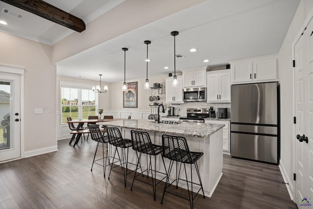 kitchen featuring appliances with stainless steel finishes, a kitchen breakfast bar, white cabinetry, visible vents, and a center island with sink