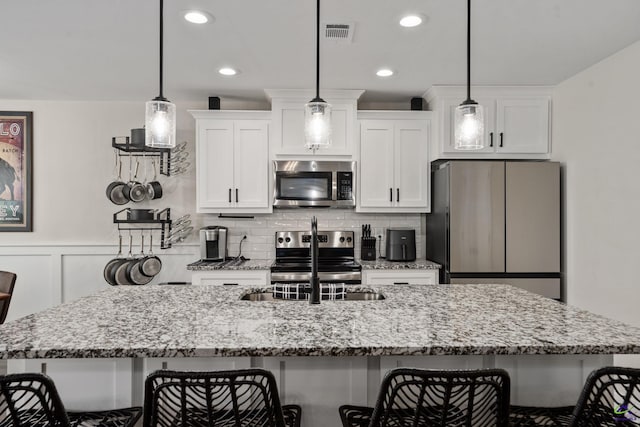kitchen featuring white cabinets, stainless steel appliances, a breakfast bar, and a sink