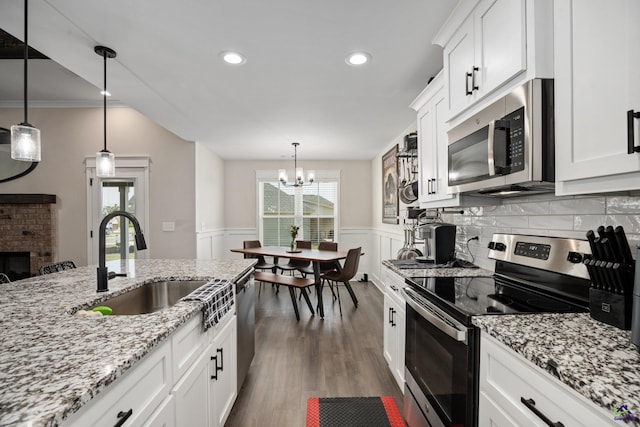 kitchen featuring wainscoting, a sink, stainless steel appliances, white cabinetry, and dark wood-type flooring