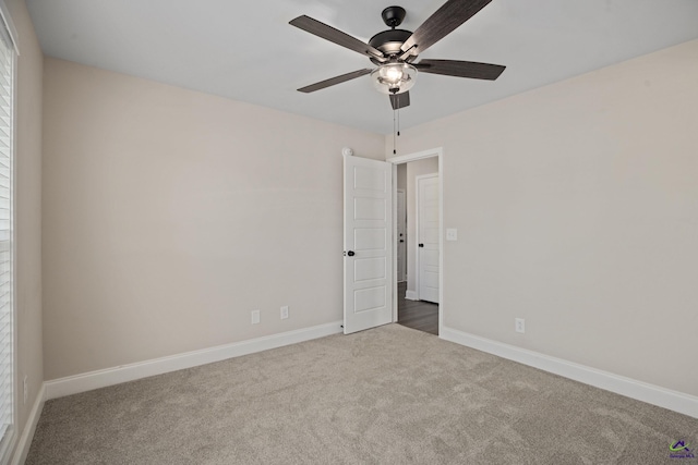 carpeted spare room featuring baseboards and ceiling fan