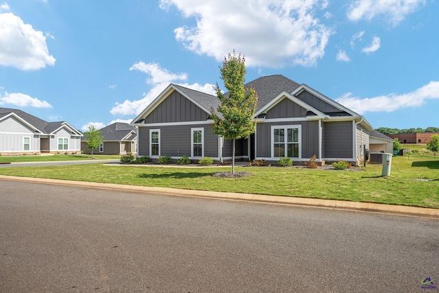 craftsman inspired home featuring central air condition unit, roof with shingles, board and batten siding, and a front lawn