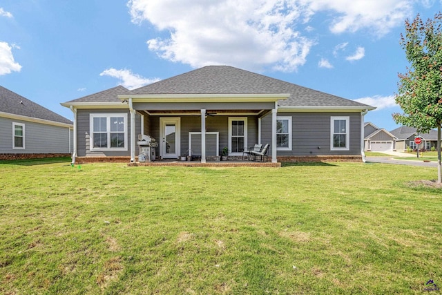 back of property featuring a lawn, a patio, and a shingled roof