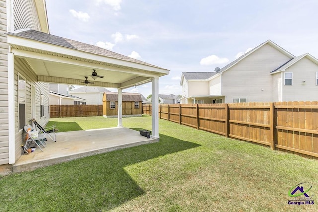 view of yard featuring a ceiling fan, an outdoor structure, a fenced backyard, a storage unit, and a patio