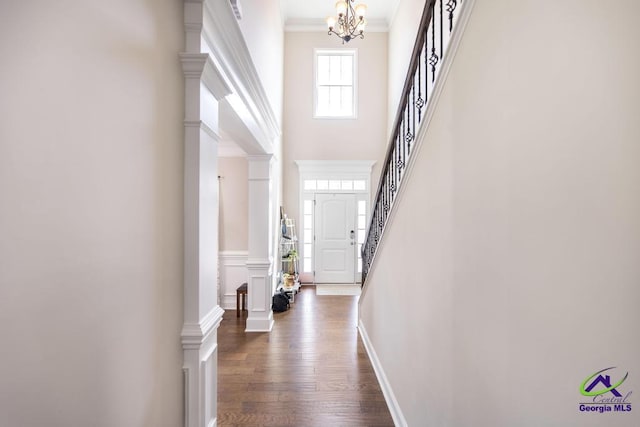 foyer with a notable chandelier, ornamental molding, a towering ceiling, dark wood-style floors, and stairway