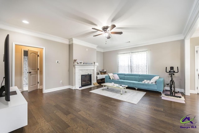 living room with crown molding, dark wood-style flooring, ceiling fan, a fireplace, and baseboards