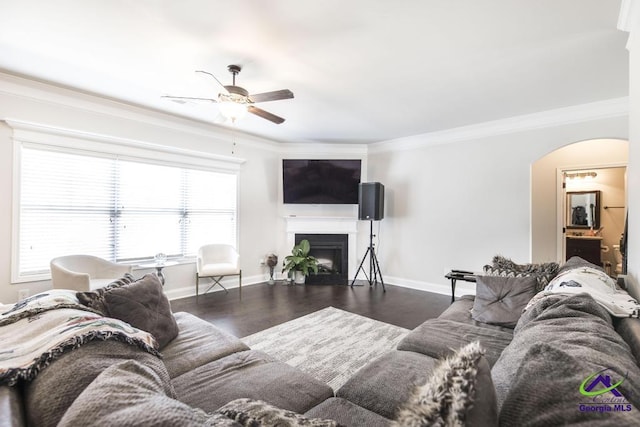 living area featuring arched walkways, a ceiling fan, wood finished floors, and ornamental molding