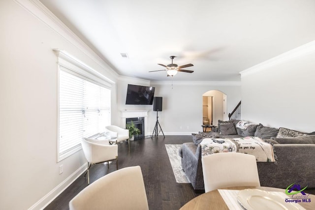 living area with arched walkways, baseboards, a ceiling fan, and a fireplace