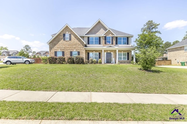 craftsman house featuring brick siding, fence, and a front lawn