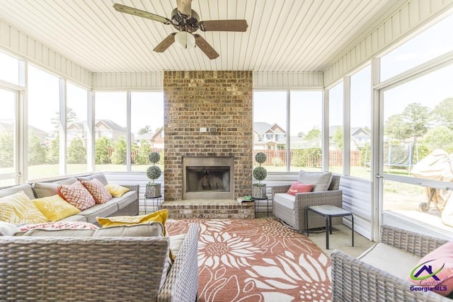 sunroom featuring ceiling fan, an outdoor living space with a fireplace, and a wealth of natural light