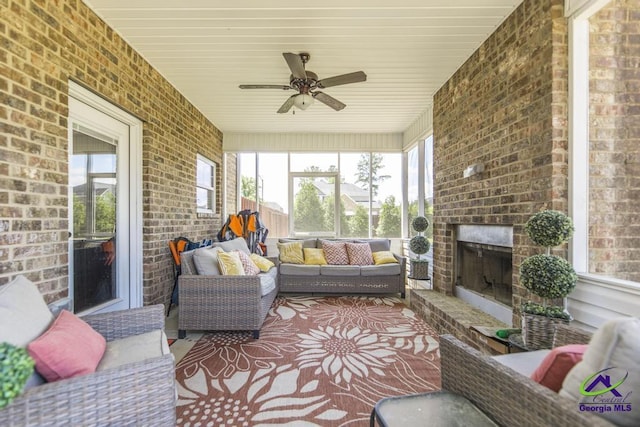 sunroom / solarium featuring a ceiling fan and an outdoor living space with a fireplace