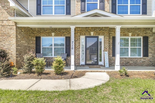 property entrance with a porch and brick siding