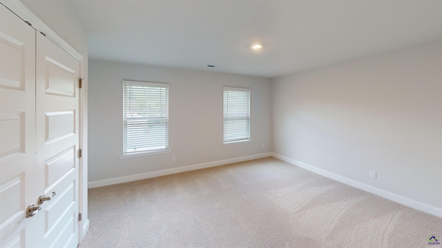 unfurnished room with baseboards, visible vents, and light carpet