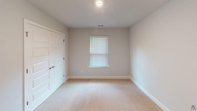 unfurnished bedroom featuring baseboards, visible vents, and light carpet