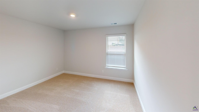 spare room featuring light colored carpet, recessed lighting, baseboards, and visible vents