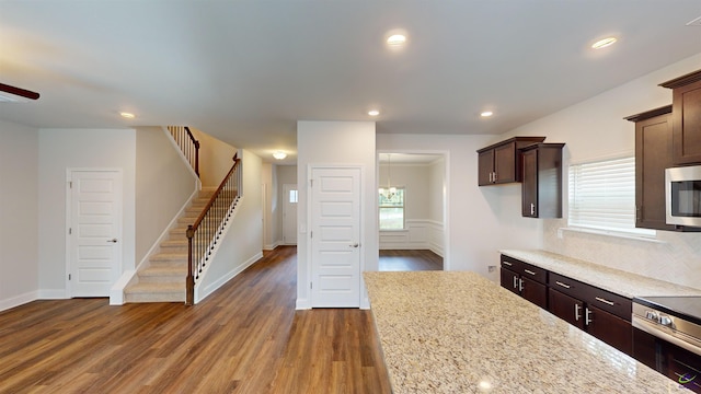 kitchen with dark brown cabinetry, light stone countertops, stainless steel appliances, a ceiling fan, and dark wood-style floors