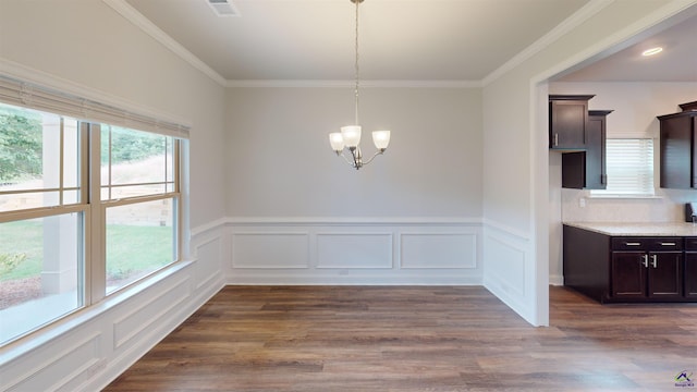 unfurnished dining area featuring an inviting chandelier, plenty of natural light, a wainscoted wall, and dark wood-type flooring
