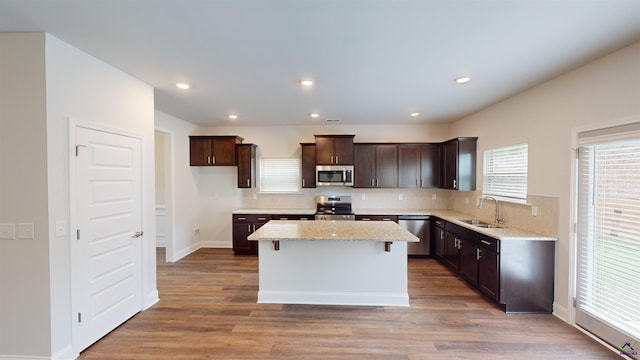 kitchen featuring a kitchen island, stainless steel appliances, dark brown cabinetry, and a sink