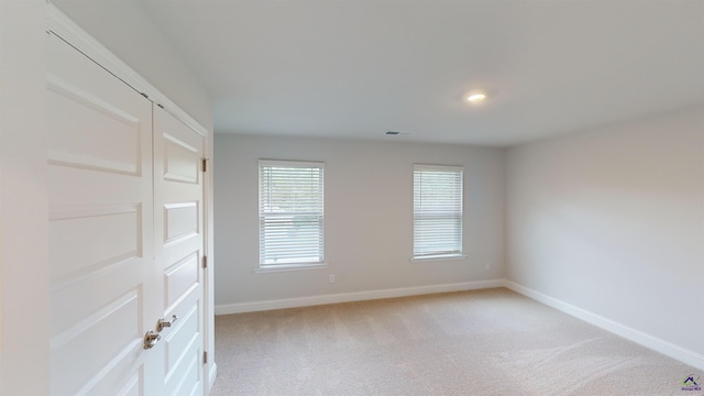 empty room with baseboards, light carpet, and visible vents