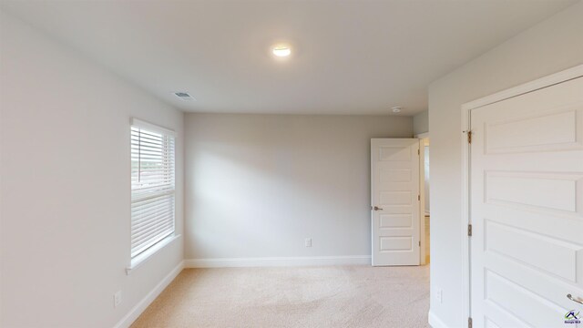 spare room with baseboards and light carpet