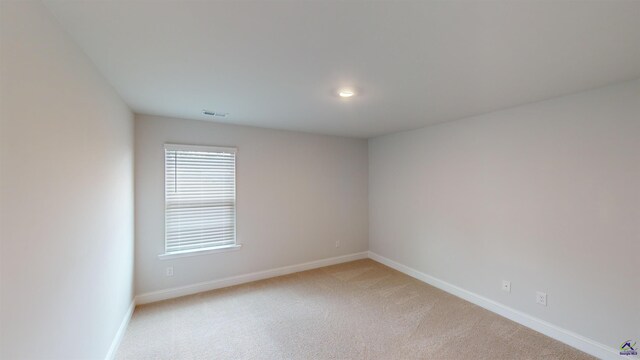 spare room featuring baseboards, visible vents, and light colored carpet