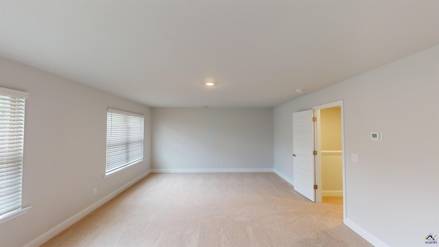 spare room featuring baseboards and light carpet