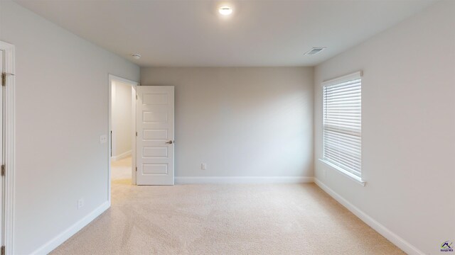 unfurnished room with baseboards, plenty of natural light, light colored carpet, and visible vents