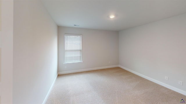 empty room with light colored carpet, baseboards, and visible vents