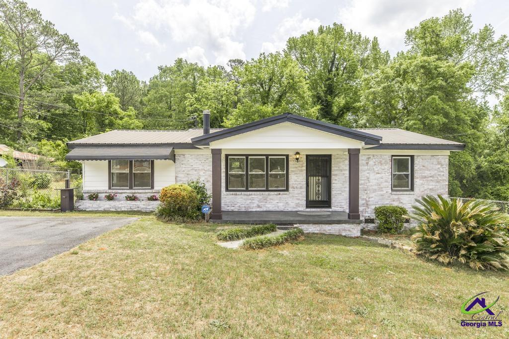 single story home featuring covered porch, metal roof, and a front yard