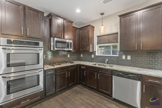 5768 Grande River Rd, Atlanta, GA 30349 - kitchen with dark brown cabinetry, light stone counters, a sink, dark wood finished floors, and appliances with stainless steel finishes