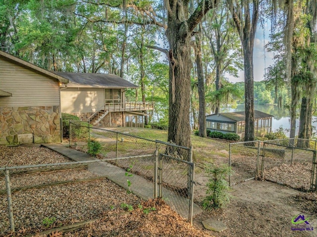view of yard featuring a gate, a fenced backyard, a deck with water view, and stairway