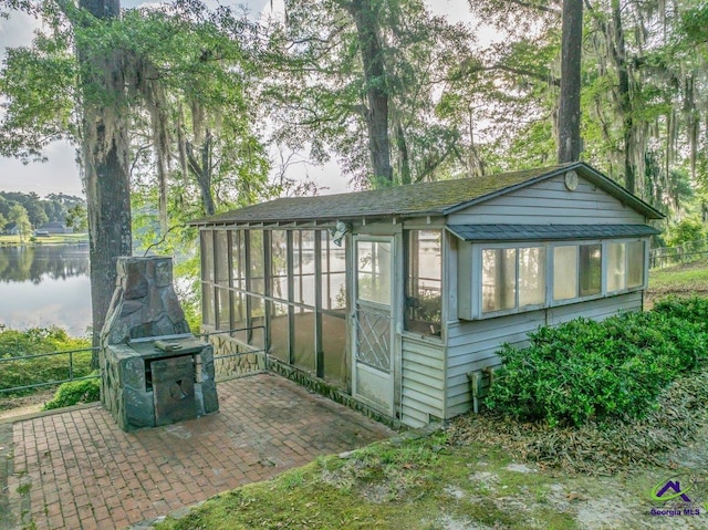 view of outbuilding featuring a water view, fence, and a sunroom
