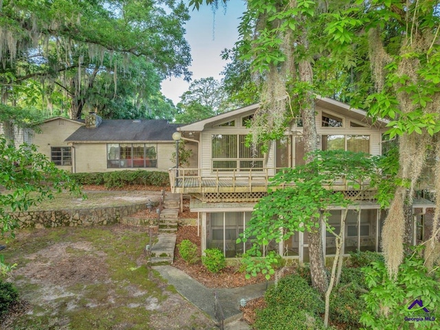 back of property with a sunroom and a deck