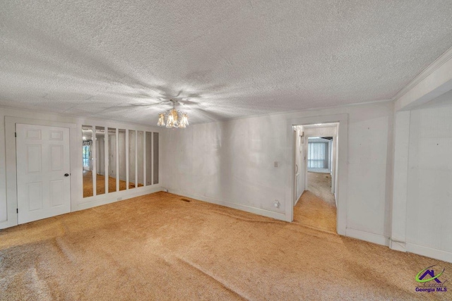 spare room with carpet floors, a textured ceiling, baseboards, and an inviting chandelier
