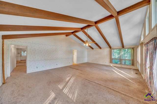 unfurnished living room with carpet flooring, wallpapered walls, plenty of natural light, and vaulted ceiling with beams