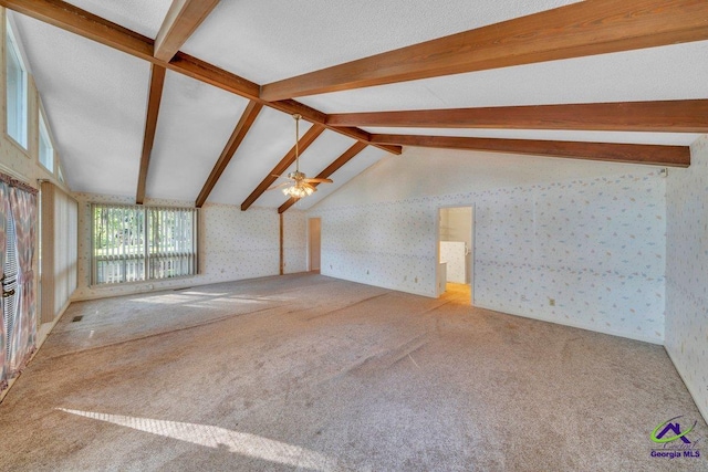 unfurnished living room featuring lofted ceiling with beams, ceiling fan, carpet, and wallpapered walls