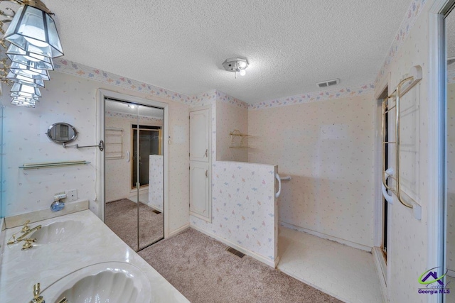 full bathroom featuring a textured ceiling, visible vents, wallpapered walls, and a sink
