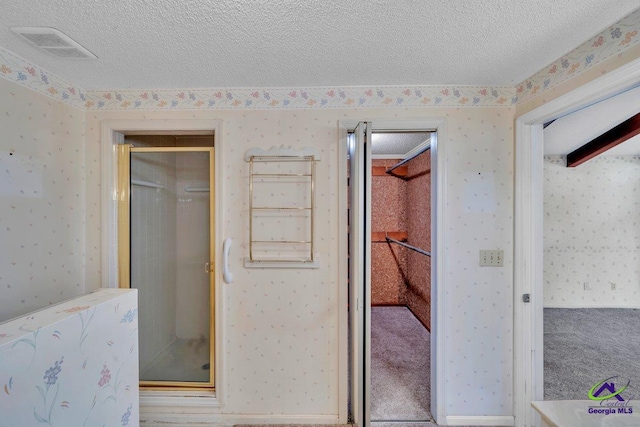full bath featuring wallpapered walls, a textured ceiling, and visible vents